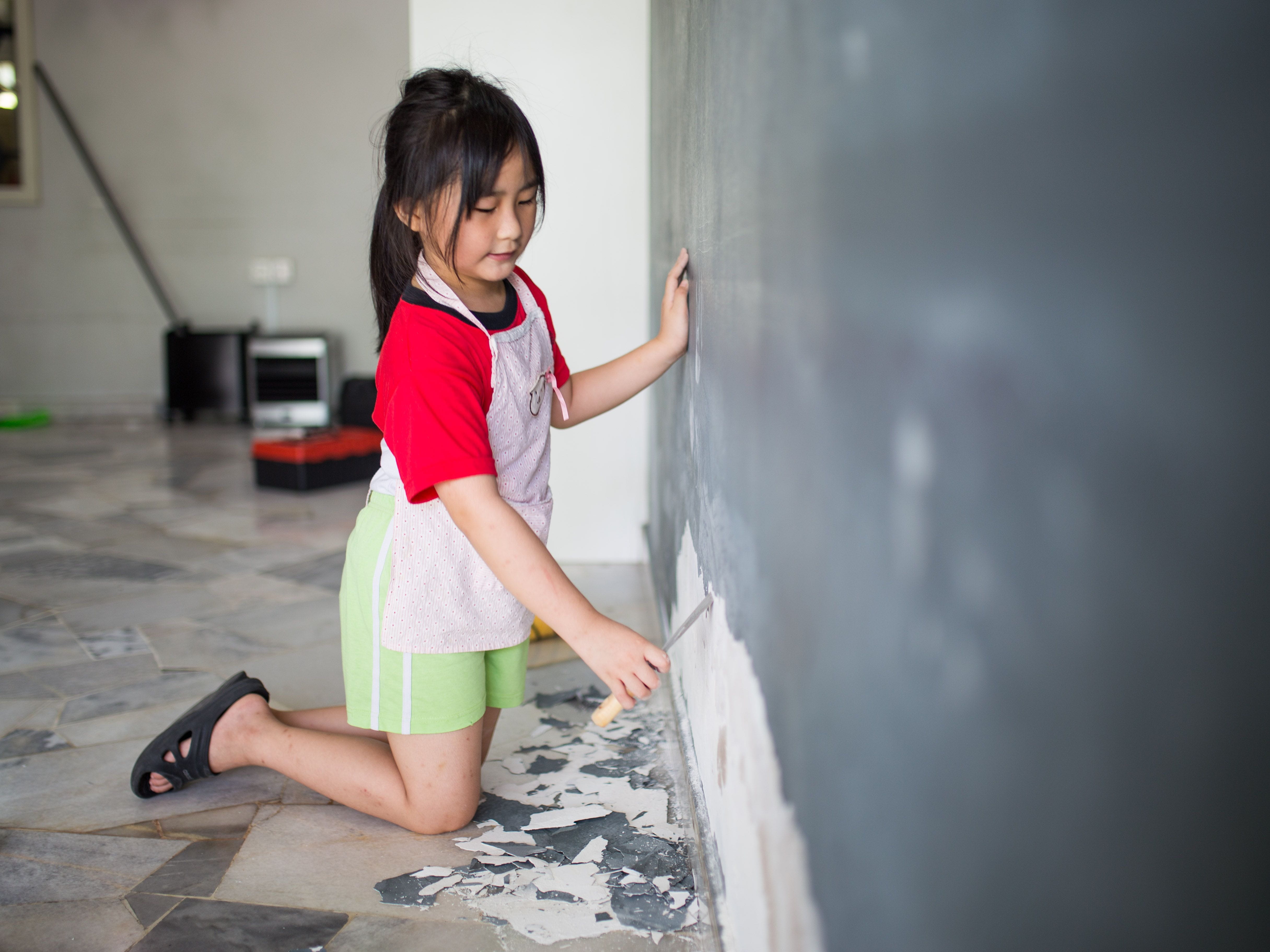 girl chipping paint off wall