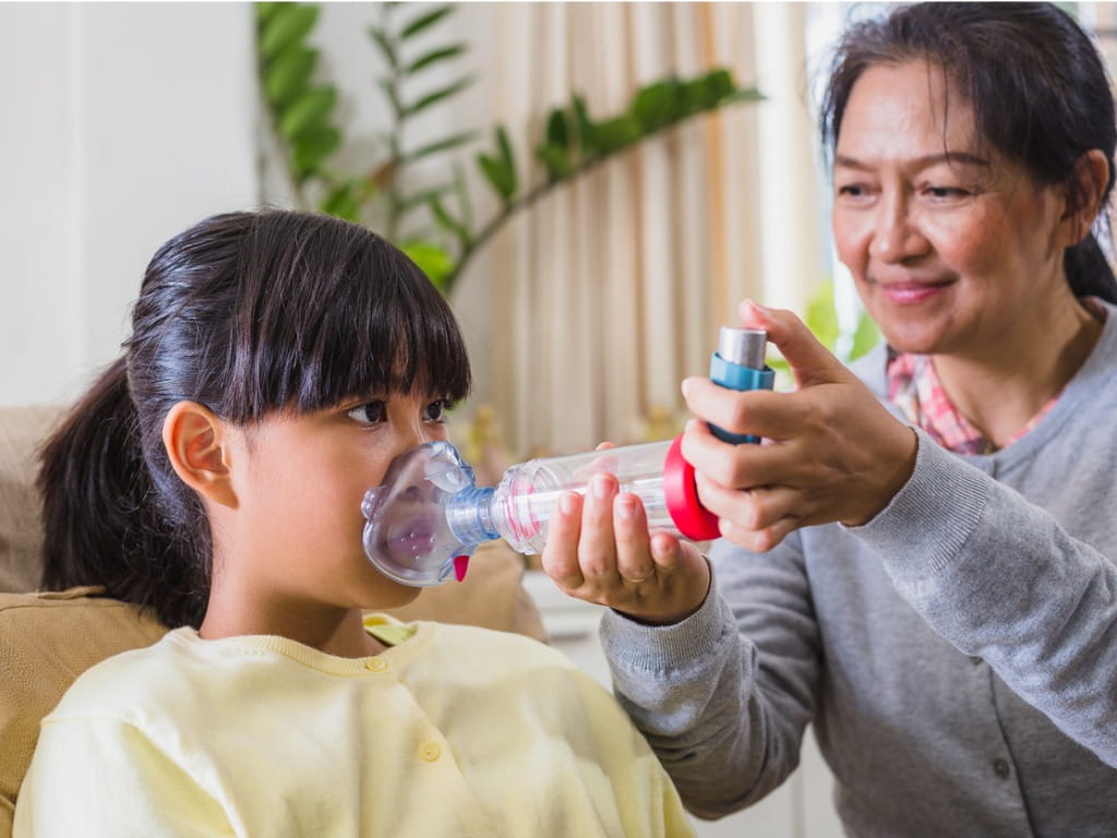 mother helping her child use an albuterol inhaler with a spacer