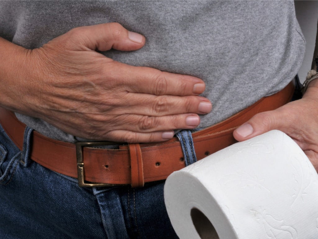 man holding his stomach and toilet paper